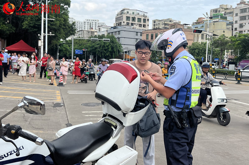 在海南省農墾中學考點，交警載著考生取回身份證后返回考點。 人民網記者 李學山攝