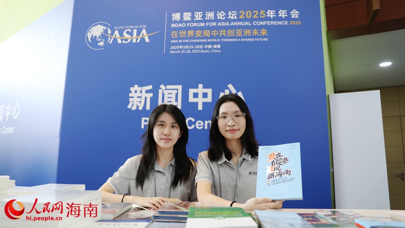在博鰲亞洲論壇新聞中心，工作人員向參會嘉賓和媒體記者推薦“營”在自貿港，“畫”說新海南宣傳冊。人民網記者符武平攝