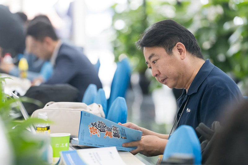 3月25日，在年會新聞中心工作區，參加年會報道工作的記者在閱讀《“營”在自貿港“畫”說新海南》中英文漫畫冊。海南省營商環境建設廳供圖