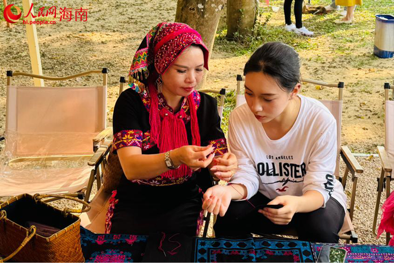 國家級黎錦傳承人指導游客編織黎錦。人民網(wǎng) 熊淑婷攝