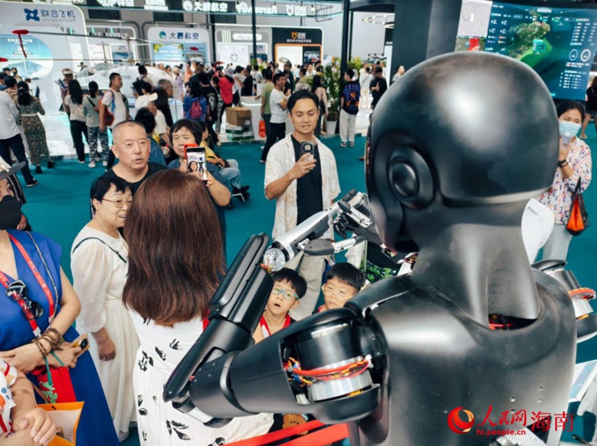 4月17日，觀眾在第五屆消博會展館中與機器人合影。人民網 符澤民攝